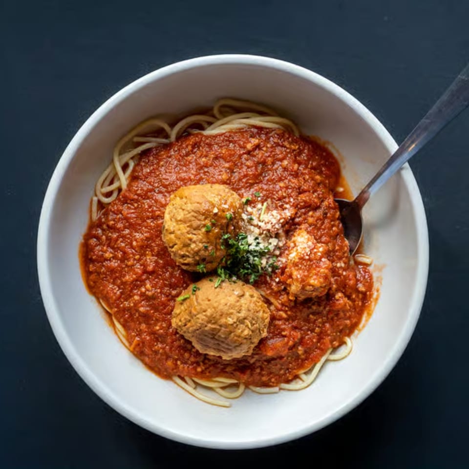 Spaghetti Western's spaghetti and meatballs, topped with parmesan and parsley, in a white bowl.