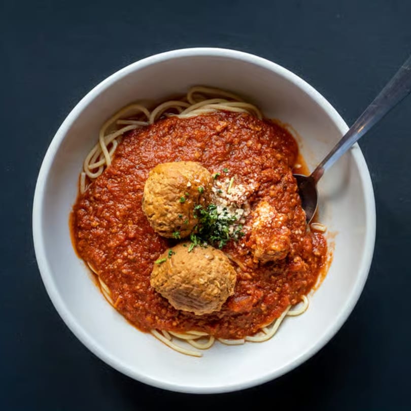 Spaghetti Western's spaghetti and meatballs, topped with parmesan and parsley, in a white bowl.